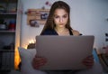 Sad and worried young girl with laptop sitting indoors, internet abuse concept.