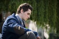 Sad, worried young man sitting outdoor in town Royalty Free Stock Photo