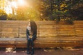 Sad young afro-haired woman sit alone on a wooden bench in autumn park at sunny warm day. Portrait of alone woman Royalty Free Stock Photo