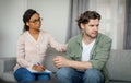 Sad young black lady doctor calms unhappy despaired caucasian male patient in office clinic interior