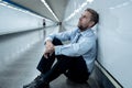 Sad young businessman jobless suffering from depression sitting depressed on ground street subway