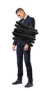 A sad young businessman stands tightly bound by large phone cords on a white background.