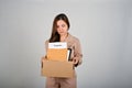 Sad young businesswoman holding a box full of her stuff, feeling sad after quitting her job