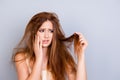 Sad young cute girl is looking at her damaged hair with shock, s Royalty Free Stock Photo