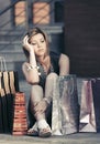 Sad young fashion woman with shopping bags sitting on city sidewalk Royalty Free Stock Photo