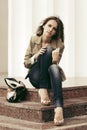 Sad young fashion woman with handbag sitting on the steps Royalty Free Stock Photo