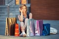 Sad young fashion woman with shopping bags sitting on sidewalk Royalty Free Stock Photo