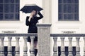 Sad young fashion woman with umbrella walking in city street Royalty Free Stock Photo