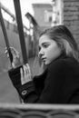 Sad young girl in black coat sitting on stairs with vintage urban background. Concept of loneliness Royalty Free Stock Photo