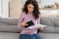 Sad young girl holding last cash money feeling anxiety about debt or bankruptcy, sitting at home. Royalty Free Stock Photo
