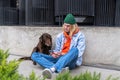 Sad young lonely man sitting on city street with dog using smartphone, having life troubles Royalty Free Stock Photo