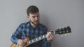 Sad young man with beard holding electric guitar and playing a rock ballad song before rock concert. Music instruments concept