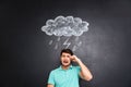 Sad young man crying over blackboard with drawn raincloud Royalty Free Stock Photo