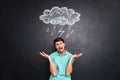 Sad young man crying over blackboard with drawn raincloud Royalty Free Stock Photo