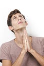 Sad young man with hands clasped praying over white background Royalty Free Stock Photo