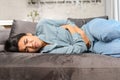 Sad young multiracial woman wearing casual clothes suffering from menstrual pain, feeling sick to her stomach, holding Royalty Free Stock Photo