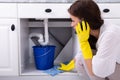 Woman Calling Plumber In Front Of Water Leaking From Pipe Royalty Free Stock Photo