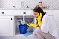 Woman Calling Plumber In Front Of Water Leaking From Pipe Royalty Free Stock Photo