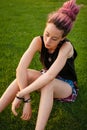 Sad young woman with dreadlocks sitting on the ground.