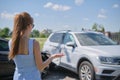 Sad young woman driver standing near her smashed car looking shocked on crashed vehicles in road accident