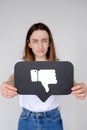 Sad young woman holding Dislike button icon of social media Royalty Free Stock Photo