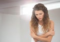 Sad young woman holding herself against window light Royalty Free Stock Photo