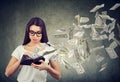 Sad woman looking at her wallet with money dollar banknotes flying out away Royalty Free Stock Photo