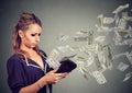 Sad young woman looking at her wallet with money dollar banknotes flying out away Royalty Free Stock Photo