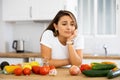 Sad woman looking at vegetable at kitchen, dieting problems