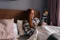 Sad young woman lying on bed under blanket holding photo in frame in hands and crying looking at picture, touching Royalty Free Stock Photo