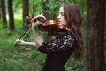 Sad young woman playing the violin romantic piece in the Park among the trees Royalty Free Stock Photo