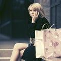 Sad young woman with shopping bags sitting on mall steps Royalty Free Stock Photo