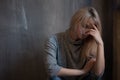 Sad young woman sitting at the wall. The young blonde. Depression and problems