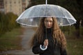 Sad young woman with umbrella in park. Seasonal portrait. Young woman with long brown heir under umbrella