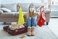 Saddened girl in mask holds swimsuits in hands