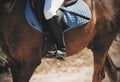 In the saddle on a Bay horse sits a rider in black boots