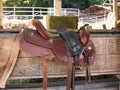 The saddle is brown on the fence in a shallow depth of field. leather saddle, harness for horses. Western saddles for