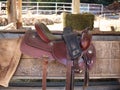 The saddle is brown on the fence in a shallow depth of field. leather saddle, harness for horses. Western saddles for