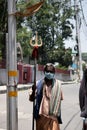 A Sadhu wearing mask going on the road, facing camera.