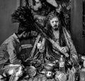 A sadhu, wearing tiger skin, make up his face with ashes, giving blessings to a boy with peacock feather at Varanasi ghat India