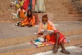 Sadhu whit his traditional dress comfortably sits and reads Indian newspaper on the Ghats of Varanasi