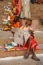 Sadhu whit his traditional dress comfortably sits and reads Indian newspaper on the Ghats of Varanasi