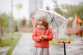 Sadness cute baby girl in the rain runs through the puddles Royalty Free Stock Photo