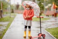 Sadness cute baby girl in the rain runs through the puddles Royalty Free Stock Photo