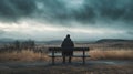 Sadness and grief, A figure sitting on a bench looking at a desolate. Royalty Free Stock Photo