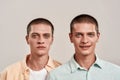 Sadness and happiness. Close up portrait of two young caucasian twin brothers looking at camera with different face Royalty Free Stock Photo