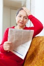 Sadness mature woman reading newspaper