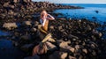 Sadness mermaid, nixie, water nymph sitting on stone. Royalty Free Stock Photo