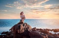 Sadness mermaid, nixie, water nymph sitting on stone. Royalty Free Stock Photo