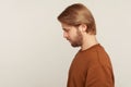 Sadness and resentment emotions. Profile of unhappy bearded man in sweatshirt looking down, bowing head Royalty Free Stock Photo